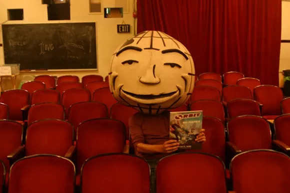 Orby holds a copy of Re-Entry: The Orbit Magazine Anthology. - Erik Maluchnik