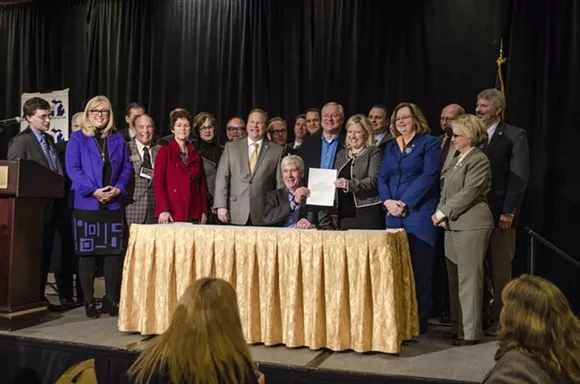 This photo is from an earlier event in Grand Rapids, where Gov. Snyder signed a bill appropriating $28 million in short-term aid for the people of Flint. But, just like this Monday's ovation, Grand Rapids-area power brokers just can't stop standing up for Snyder. - Photo courtesy Gov. Snyder's office