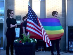 A rainbow pride flag flies next to the American flag at a Sunday vigil in Ferndale for victims of a mass shooting at a gay nightclub in Orlando that left 50 dead. - Photo by Dustin Blitchok