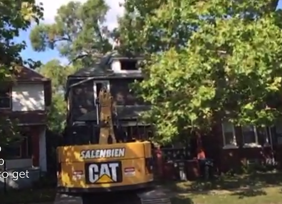 Guy climbs on roof in protest of demolition of neighboring house