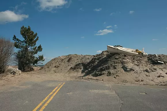 "Boat with Christmas Decorations on an Engineered Sand Dune after Hurricane Sandy, Monmouth Beach, New Jersey, 2013. Elevation Ten Feet. N 40.32709 W 73.97551." - Photo by John Ganis.