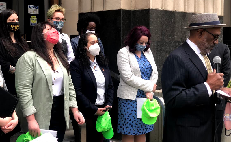 Attorney David Robinson, right, is representing five legal observers from the National Lawyers Guild, holding their signature neon green hats, who say they were brutalized by Detroit police last summer. - Jack W. Schulz