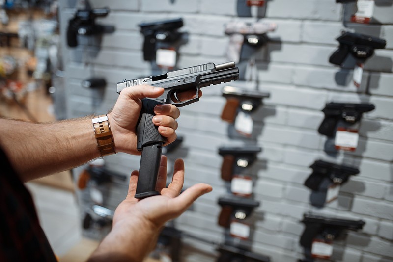 Man choosing new handgun in gun shop. - Shutterstock