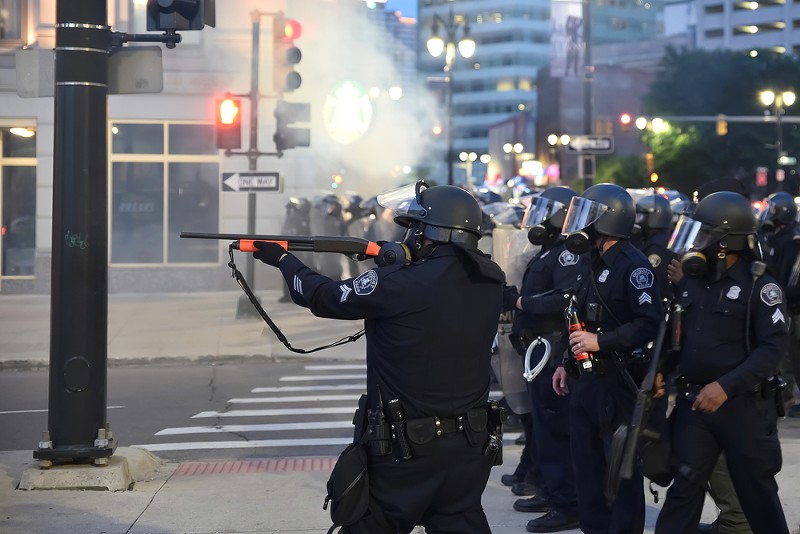 Detroit cop fires at protesters. - LESTER GRAHAM / SHUTTERSTOCK.COM