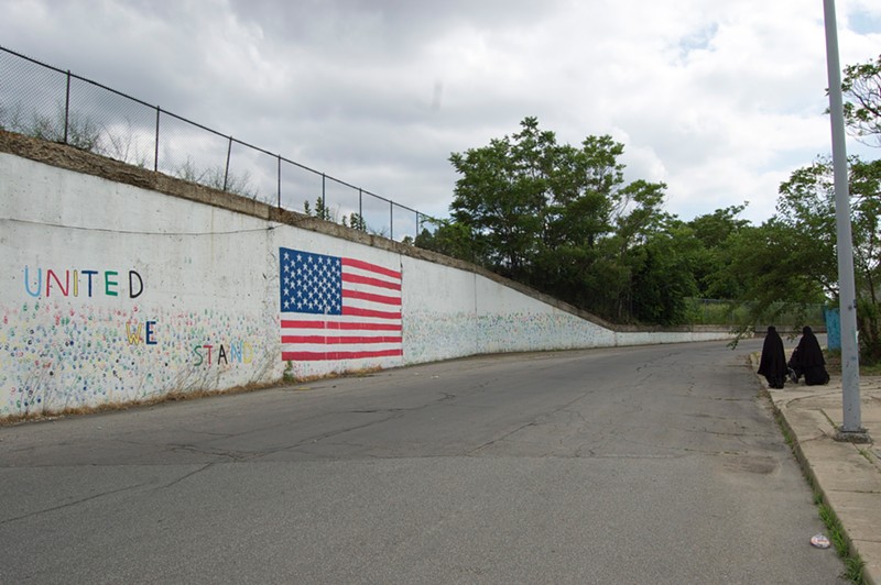 Muslim women walking near an American flag mural in Hamtramck, Michigan. - LEE DEVITO