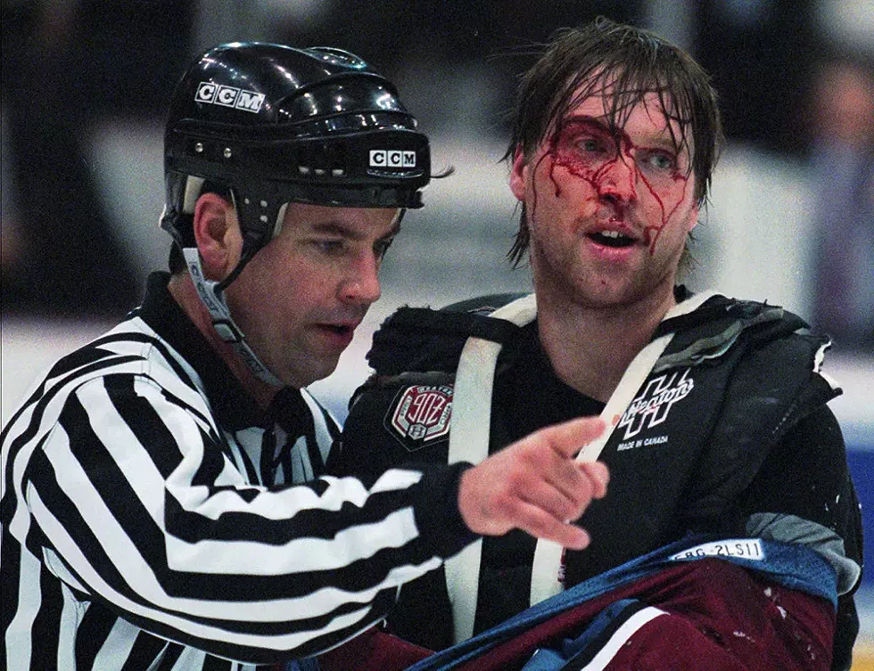 Linesman Dan Schachte leads a bleeding Colorado Avalanche goaltender Patrick Roy to his bench after Roy was involved in a first-period brawl with Detroit Red Wings' goaltender Mike Vernon in Detroit on Wednesday, March 26, 1997. - AP Photo/Tom Pidgeon