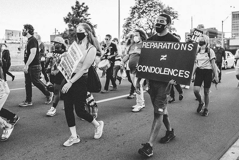 A protester in Detroit holds a sign in support of reparations. - Viola Klocko