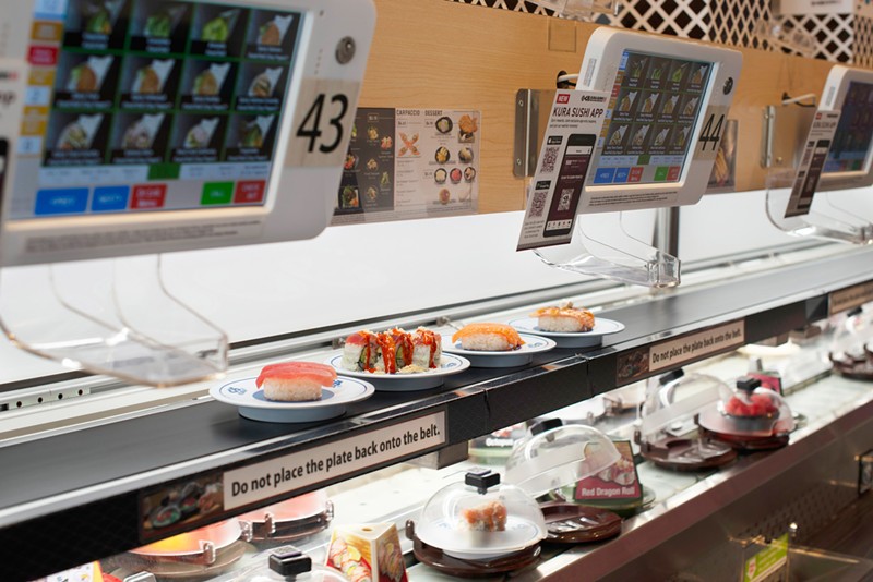 A conveyor belt delivers plates of sushi to customers. - Emily J. Davis for Kura Sushi