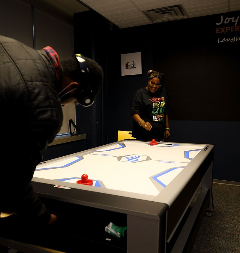 Matthews plays air hockey with one of the center’s youth. - se7enfifteen