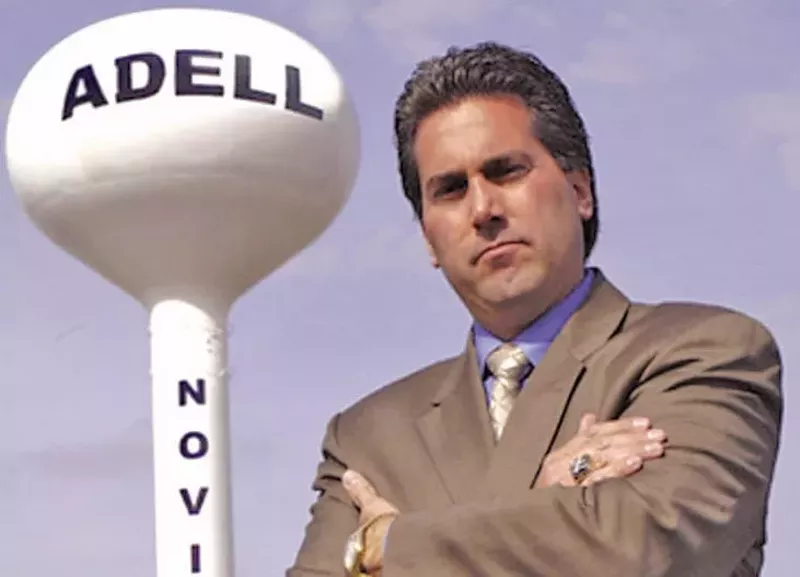 910AM Superstation owner Kevin Adell posing next to a water tower bearing his name in Novi. - Courtesy photo