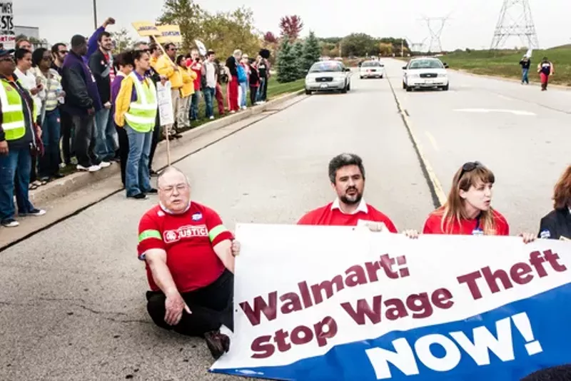 Wage theft protesters stage a sit-down protest to block the entrance of the Walmart distribution center in Elwood, Ill. - Photo courtesy Shutterstock