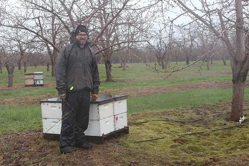 Michal Peterson next to a hive on Wunsch Farms. May 1, 2025. - Izzy Ross/IPR News