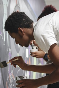 A student at Detroit's Southeastern High School, where there is no formal art program, paints a mural as part of a new partnership between the school and the Heidelberg Project.