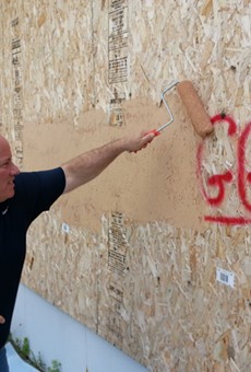 Detroit Mayor Mike Duggan buffs graffiti bearing his name in 2013.